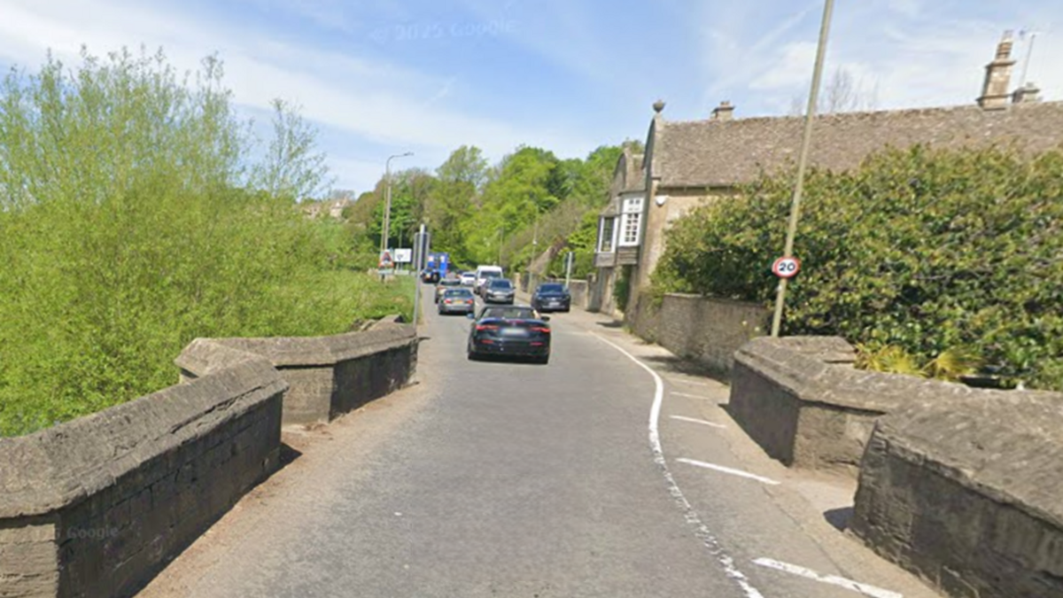 A single-track road over a bridge with historical low stone walls