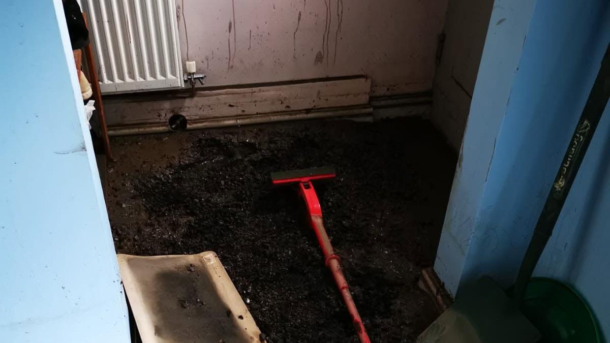 Deep slurry and debris seen in a house. A radiator is in the backgroun.