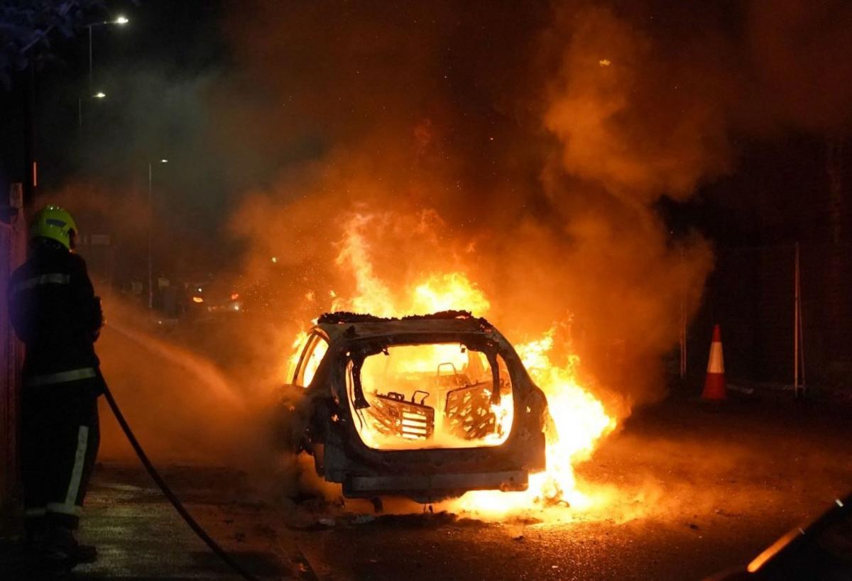 Firefighters tend to a burning police car burns as officers are deployed on the streets of Hartlepool