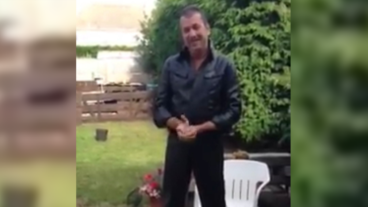 Phil Brock standing in a garden. He has short dark hair and is wearing a dark leather jacket, with his hands clasped together.
