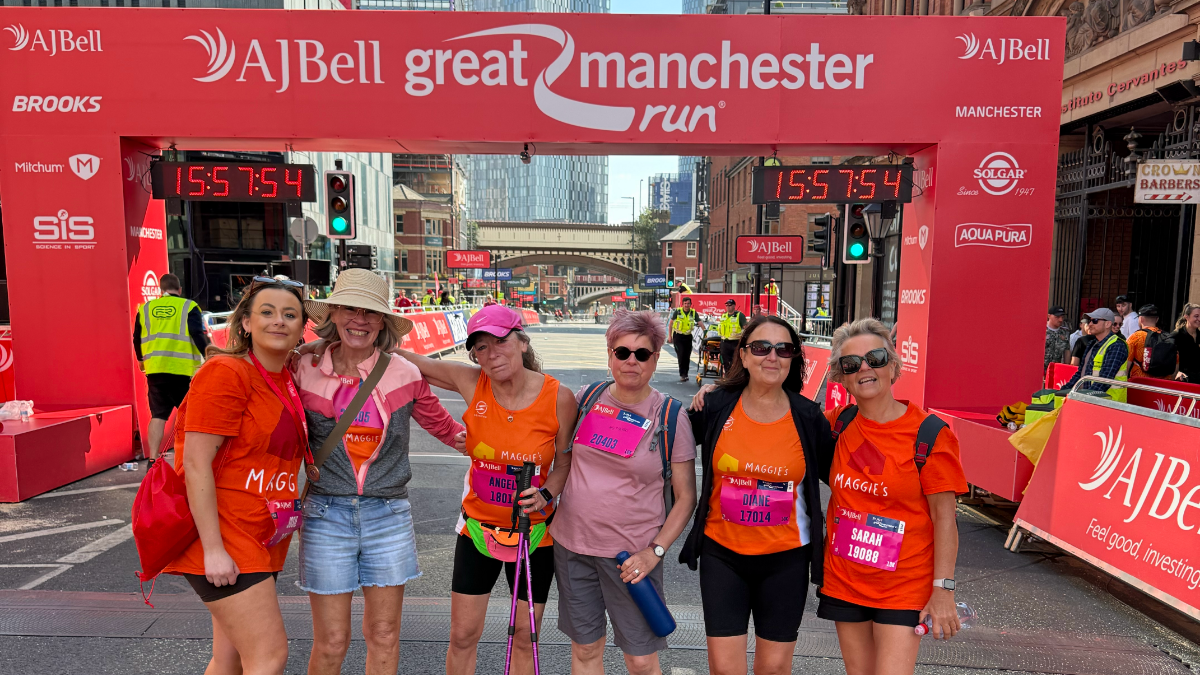 Angela (middle) stands with five members of her running team in front of the AJ Bell Great Manchester Run finish line. All but one wear orange T-shirts with Maggie's written on the front in white letters