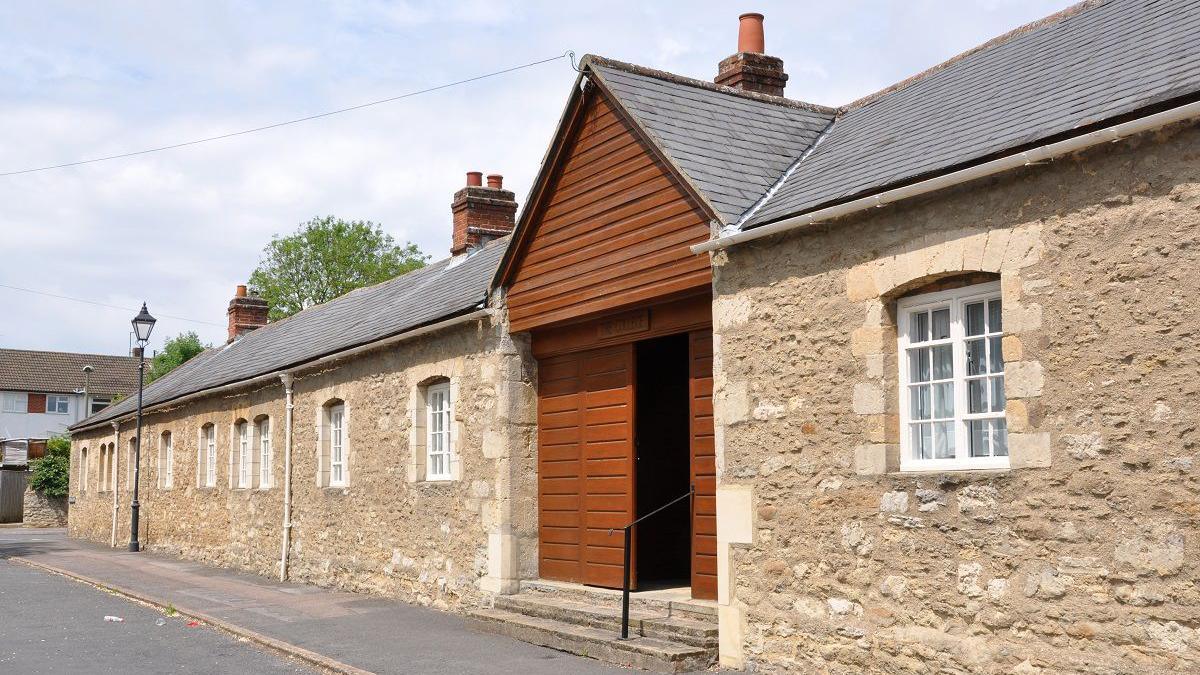 The College in Littlemore is a large stone building with a big wooden door way.
