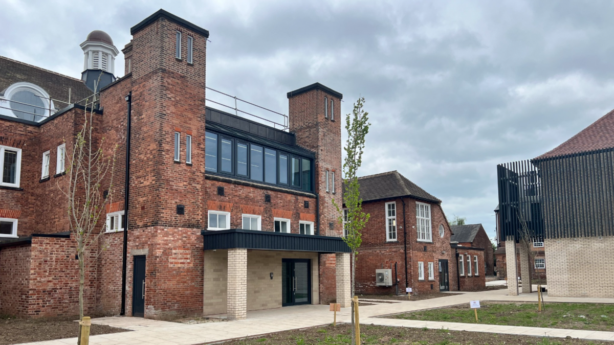 Large Victorian orange brick building with large rectangular white framed windows offset by courtyard