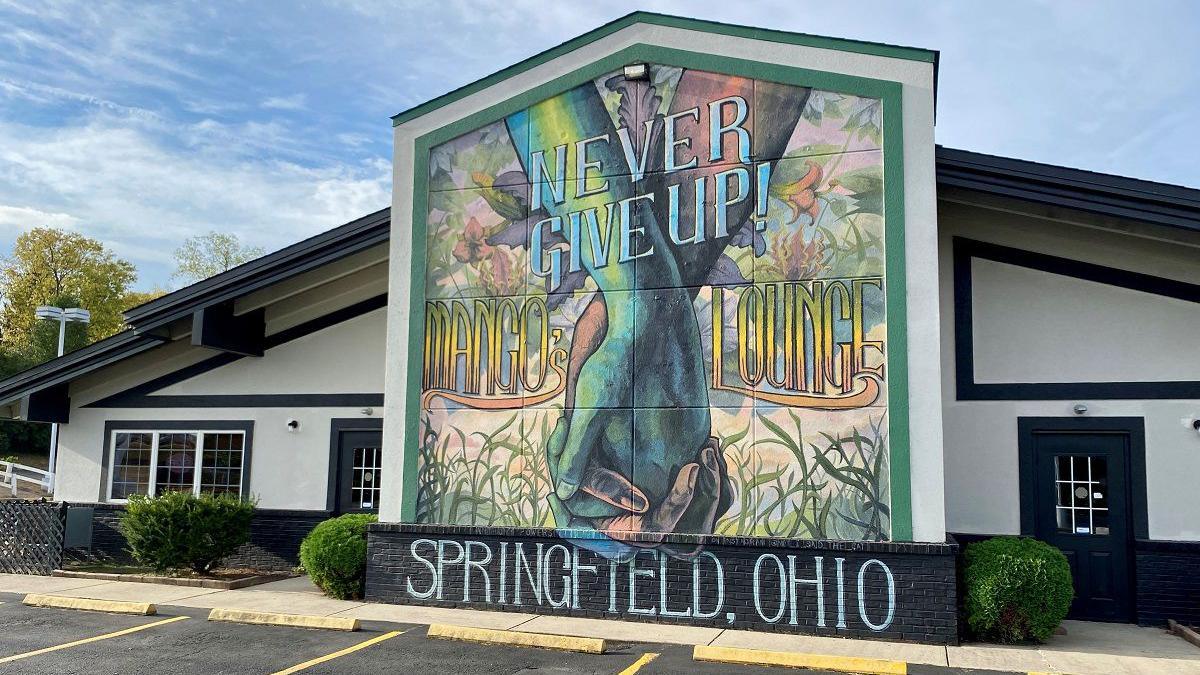 A mural saying "Never Give Up... Springfield Ohio" and showing two hands clasped