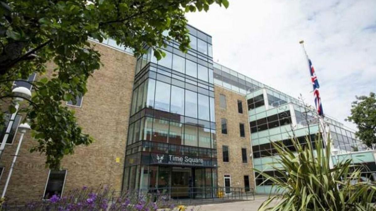 Bracknell Forest Council's building. It has all glass windows at the centre of the building which protrudes the rest of the sandy-coloured brick frontage. there is a sign above the door on the glass that reads Time Square Bracknell Forest Council