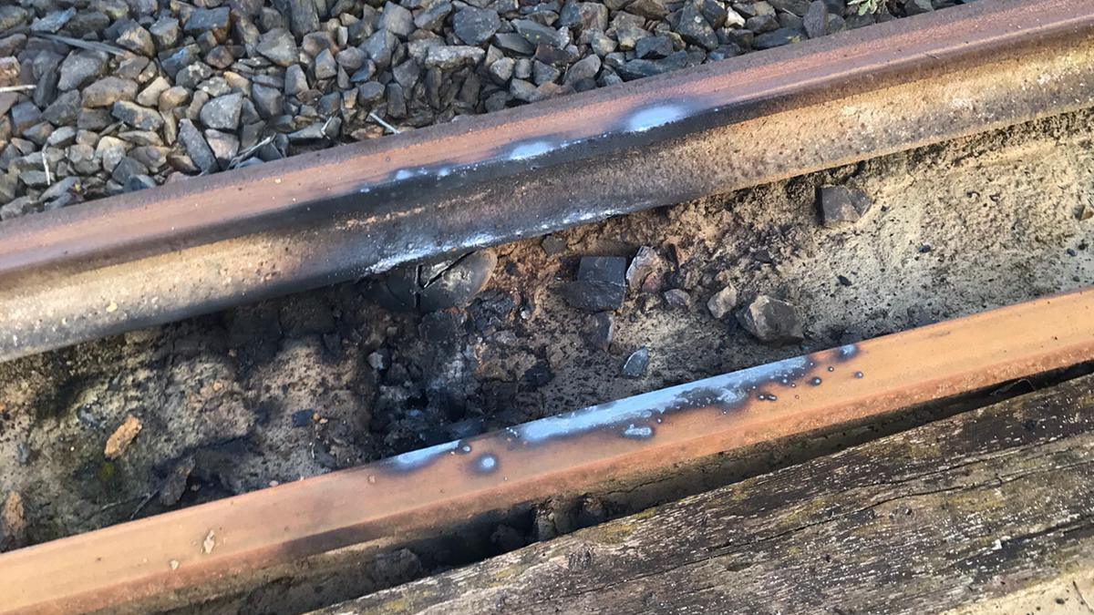 A close up image of a train track showing discolouration and damage to a metal rail 