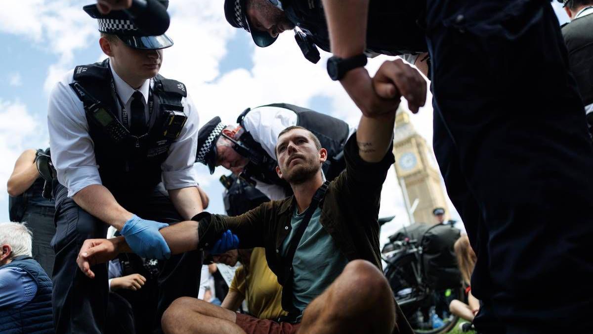 Police officers arrest a man during a mass protest in Parliament Square