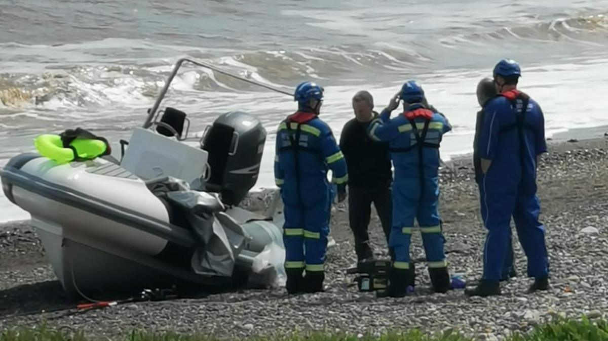 Officers on a beach next to a dinghy