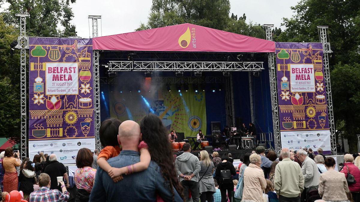 Pink and purple stage set up in park with crowds watching