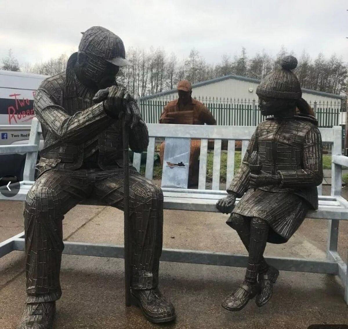 A life-size man and a young girl are cast out of metal. They are sitting on a bench, appearing to talk with one another.