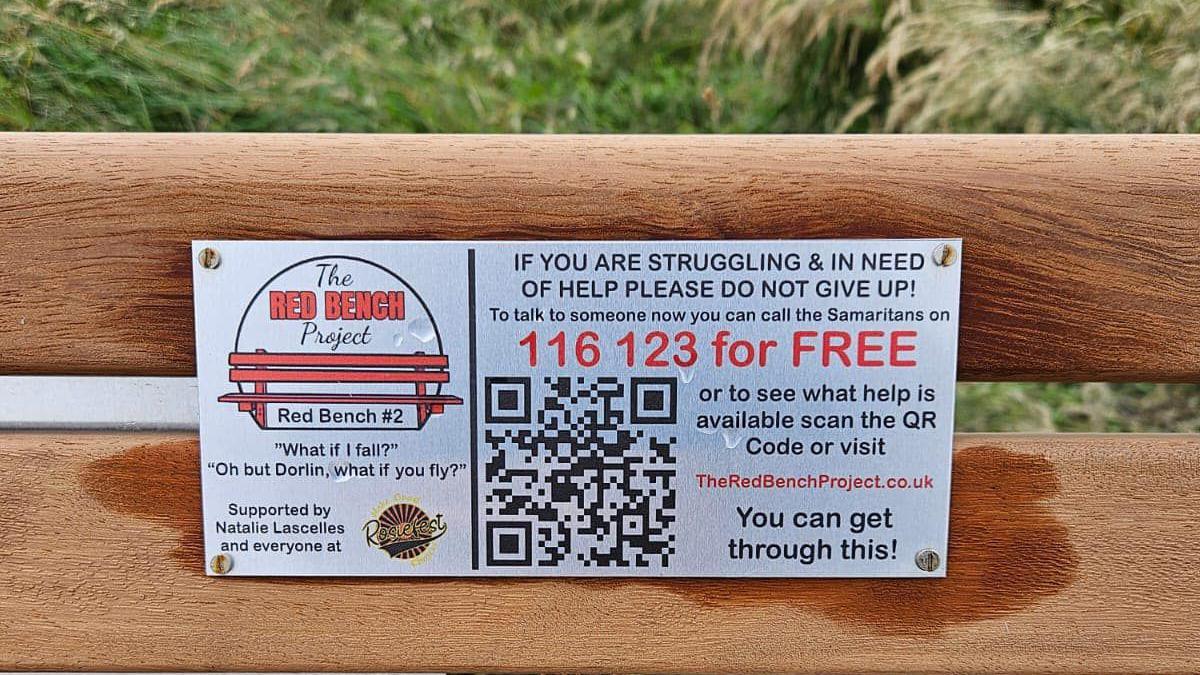 A sign on the 'Red Bench Project' bench has the Samaritans number on it, a QR code and a quote which reads: "What if I fall?" - "Oh but Dorlin, what if you fly?" 