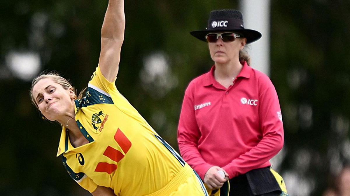 Sophie Molineux bowling as an umpire watches on