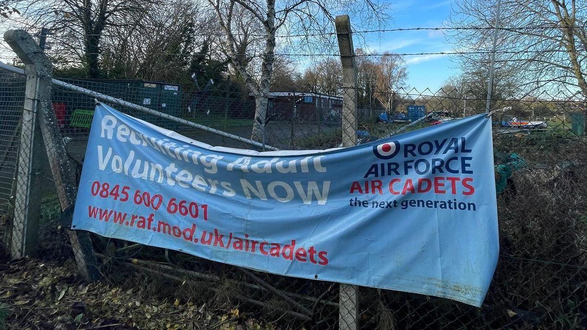 A banner for the RAF Air Cadets in Chippenham. It is blue and draped on a wire fence.