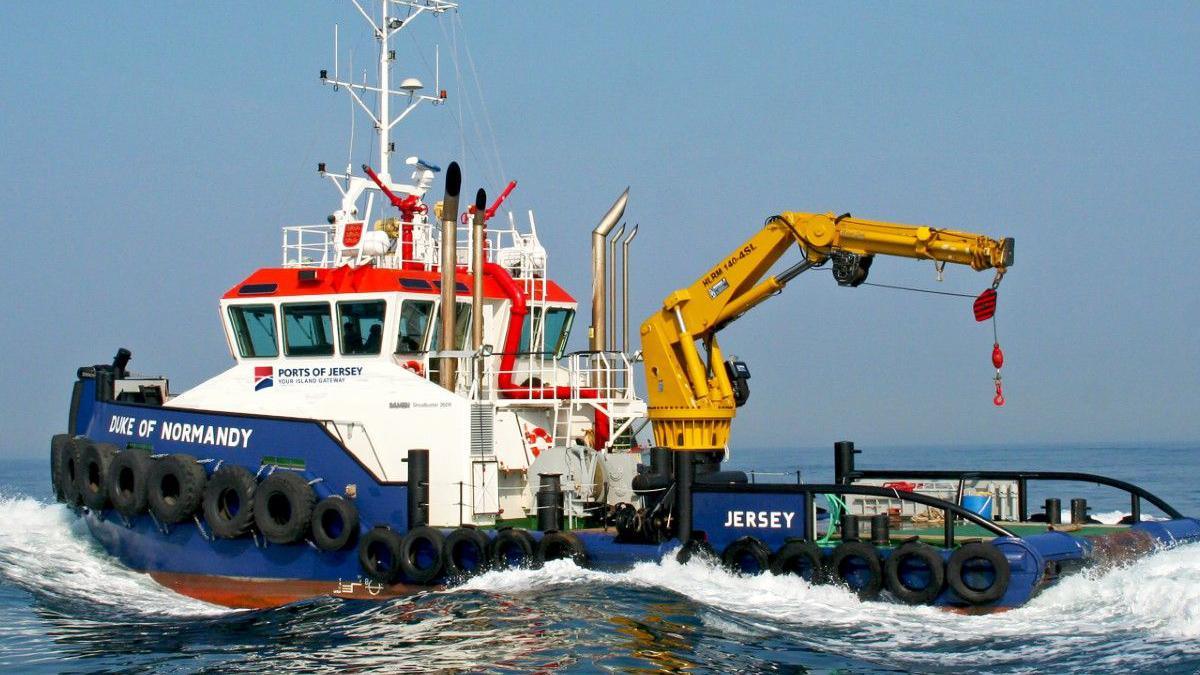 A workboat called Duke of Normandy, registered in Jersey. It has a blue hull, white cabin and a yellow hydraulic lifting arm.