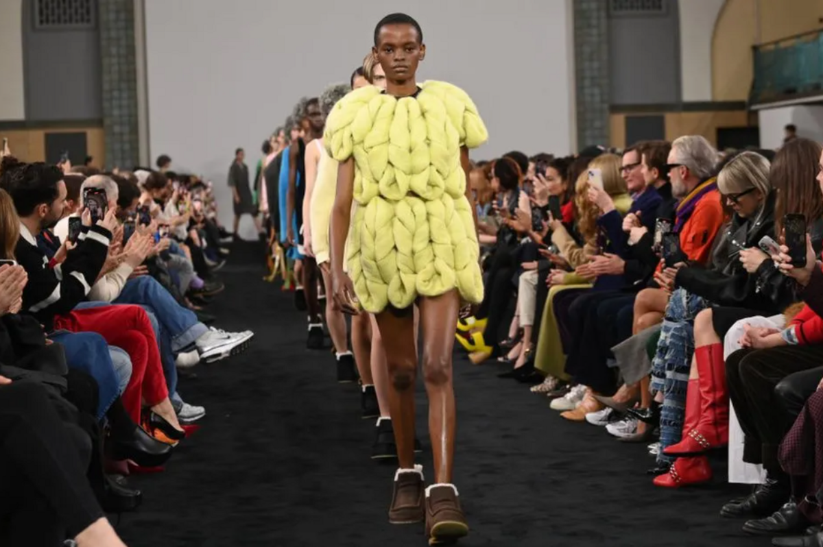 Model at London fashion week wearing yellow skirt and top with brown boots