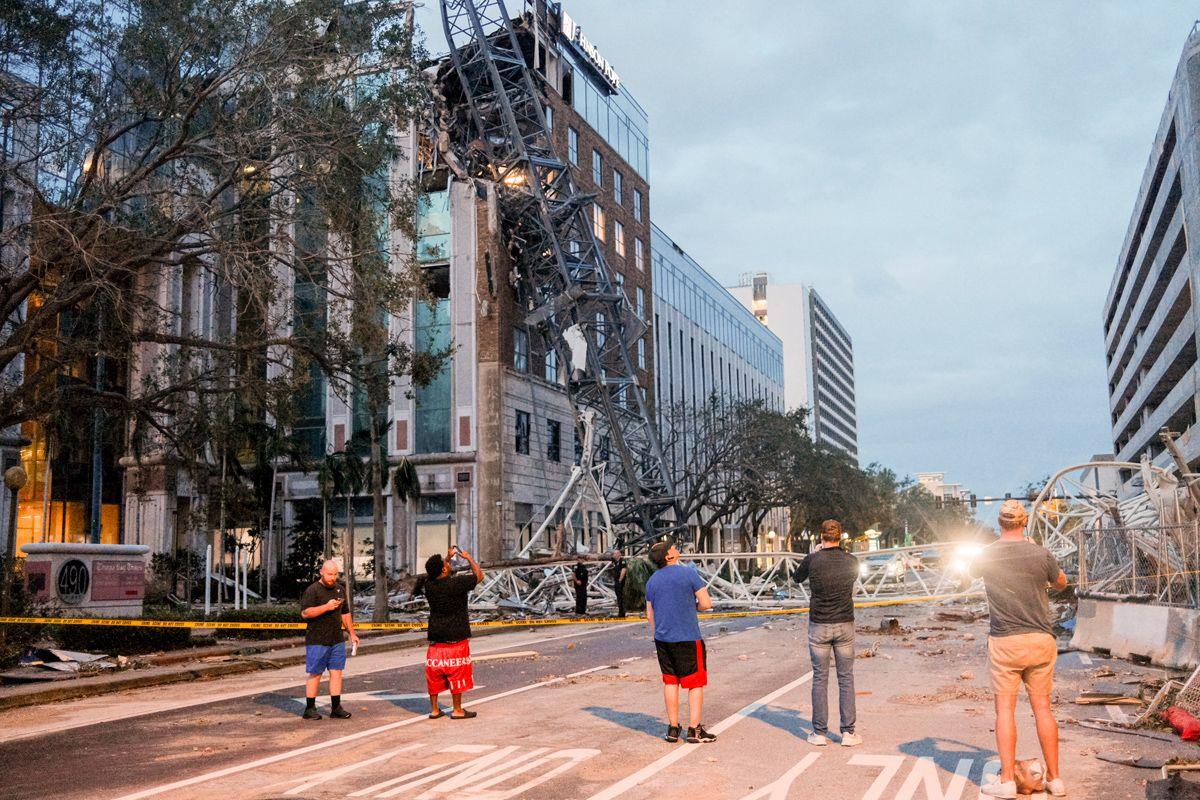 Residents inspect property damage as a crane is leaning against a damaged building on a street after Hurricane Milton made landfall in St. Petersburg, Florida, US, on Thursday, Oct. 10, 2024