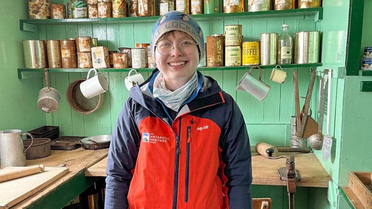 Aoife McKenna in the museum on Port Lockroy. Behind her are old tins and jars on shelves.