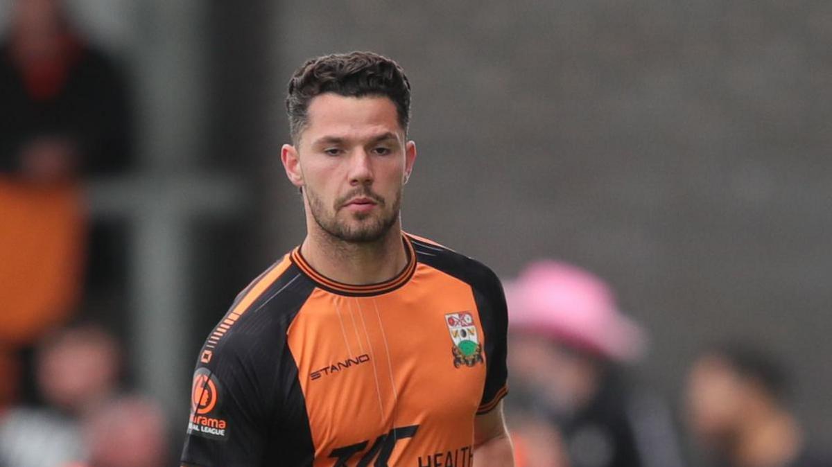 Nik Tavares in orange shirt playing for Barnet in May last season