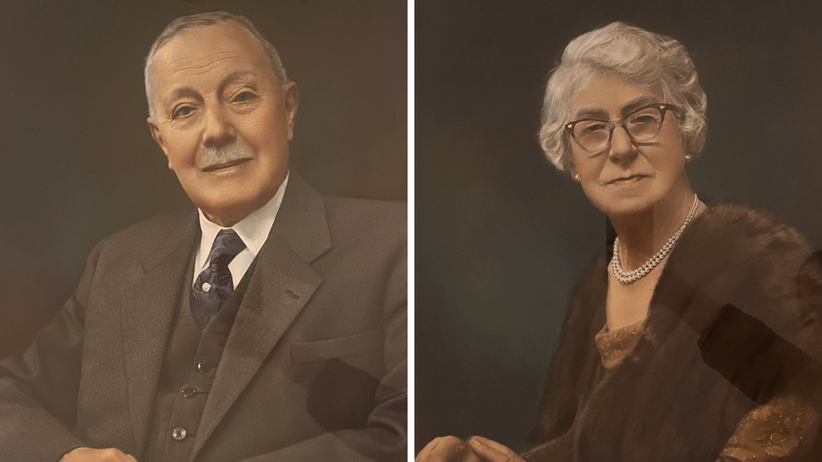 Portraits of Fred Mitchell (right) and his wife Clarrie (left). He has grey hair and a grey moustache, and is wearing a grey waistcoat and jacket, white shirt and blue tie. She has short, grey hair and is wearing a pearl necklace, glasses and fur jacket