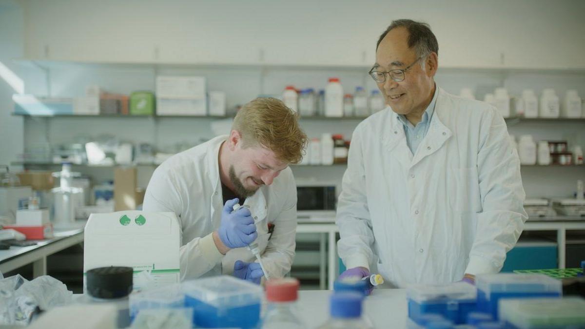 Two men wearing white lab coats in a science lab.