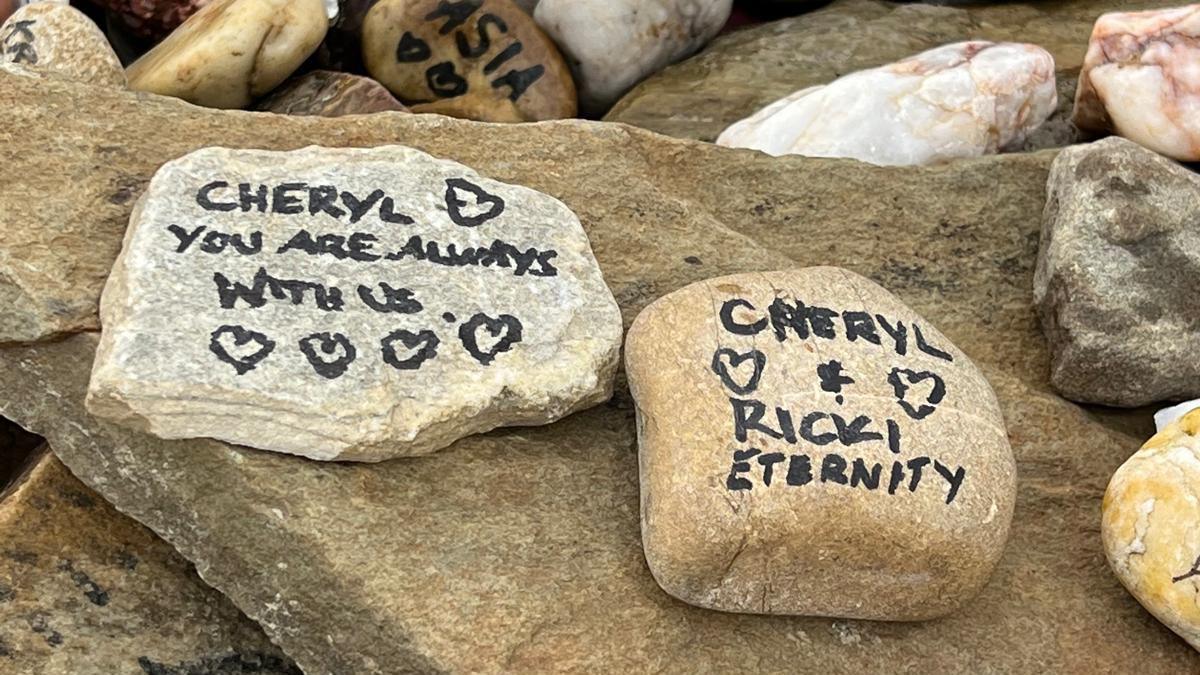 Rocks with names of loved ones written on with black marker. Cheryl Grimmer's name is among them