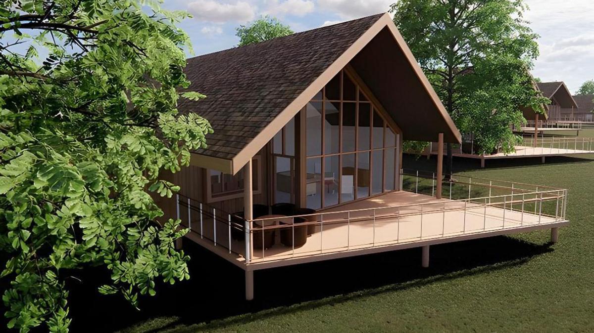 An artist's impression of one of the lodges at the site. It has a wide outside area which is raised, large glass doors and windows and a slanted roof. It is surrounded by trees and has another lodge in the background. The lodges are spaced apart.