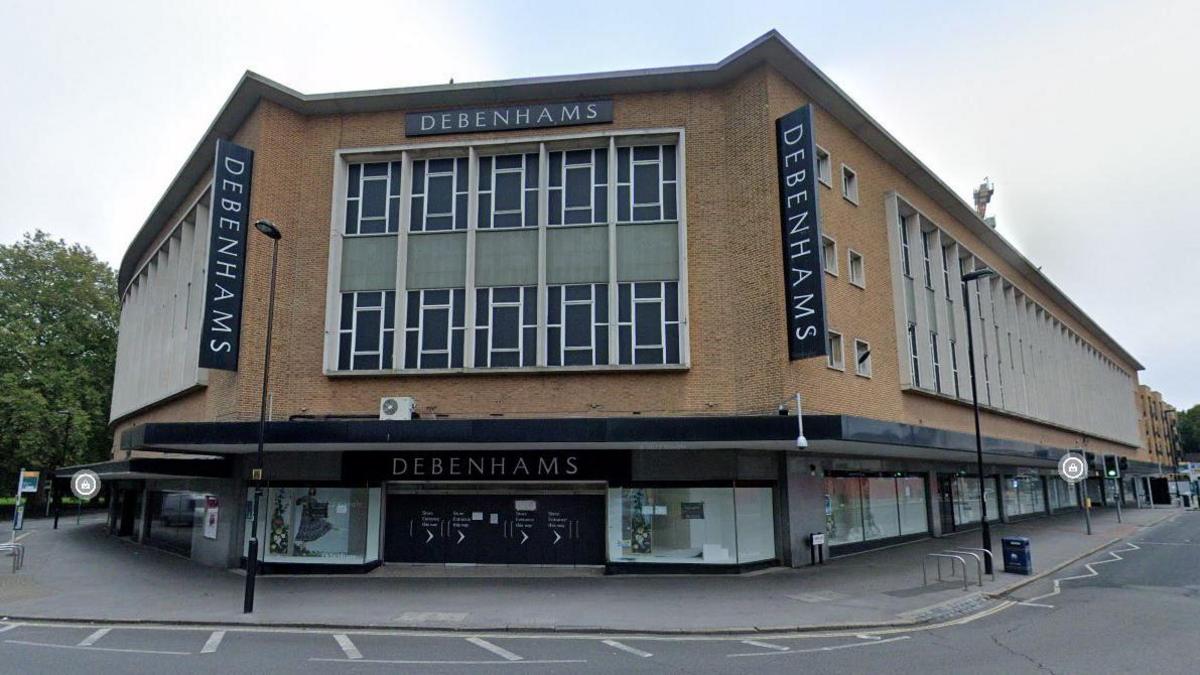 The facade of the Debenhams store in Southampton, as seen from the roundabout on Queensway. To the left there is a tree in Hoglands park.