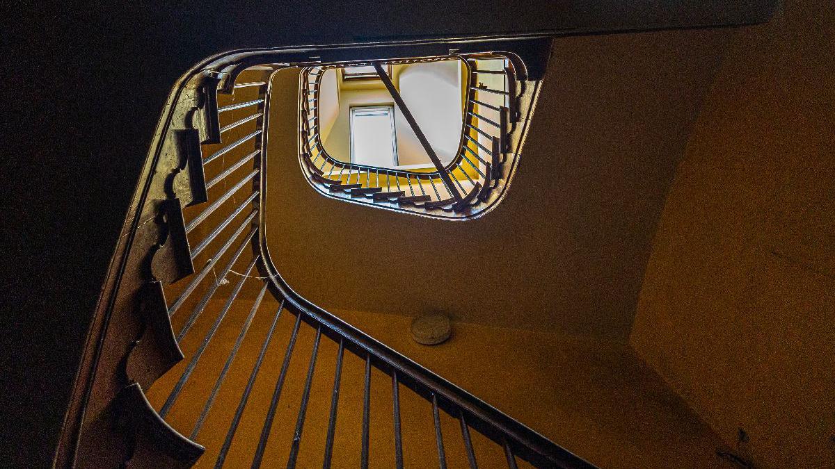 View looking up the middle of a curved staircase with bannisters wrapping around a central void.