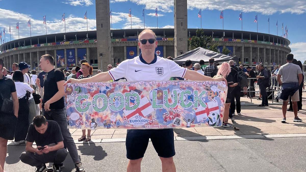 School vice principal Jamie Morgan holding the banner outside the stadium in Berlin