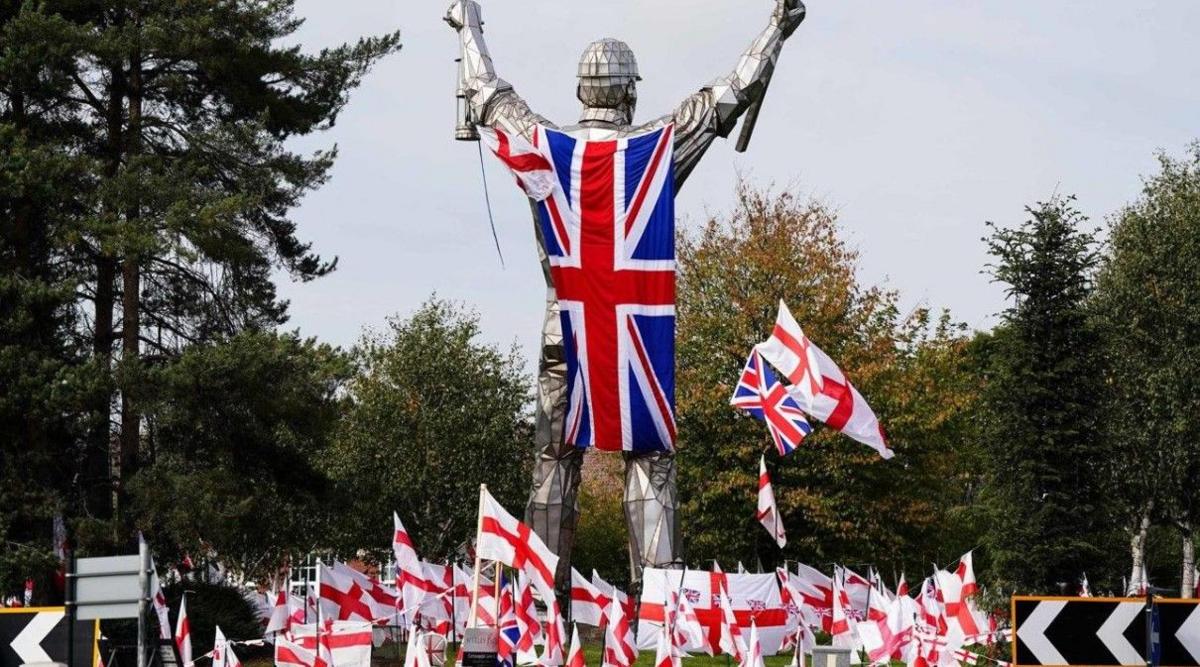 Flags are on a roundabout near a flag on a statue.