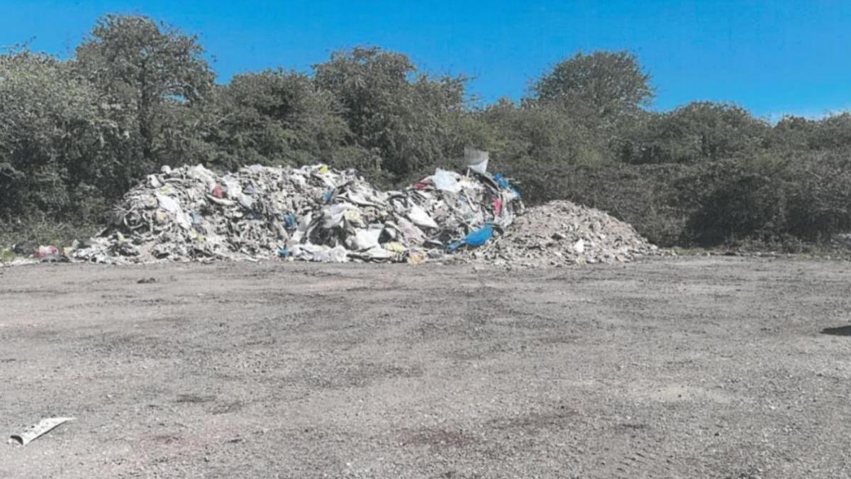 A large pile of waste flytipped on a site near a housing estate