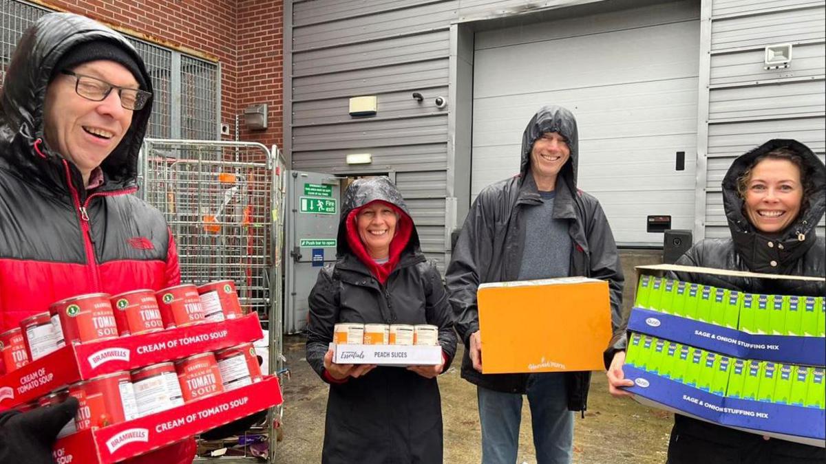 Members of the congregation, wearing coats, holding cans of food