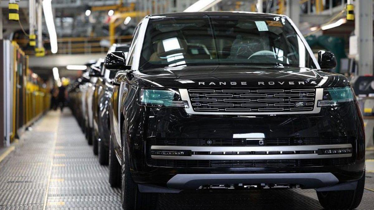 The front of a black Range Rover on a car production line, with other vehicles behind it.
