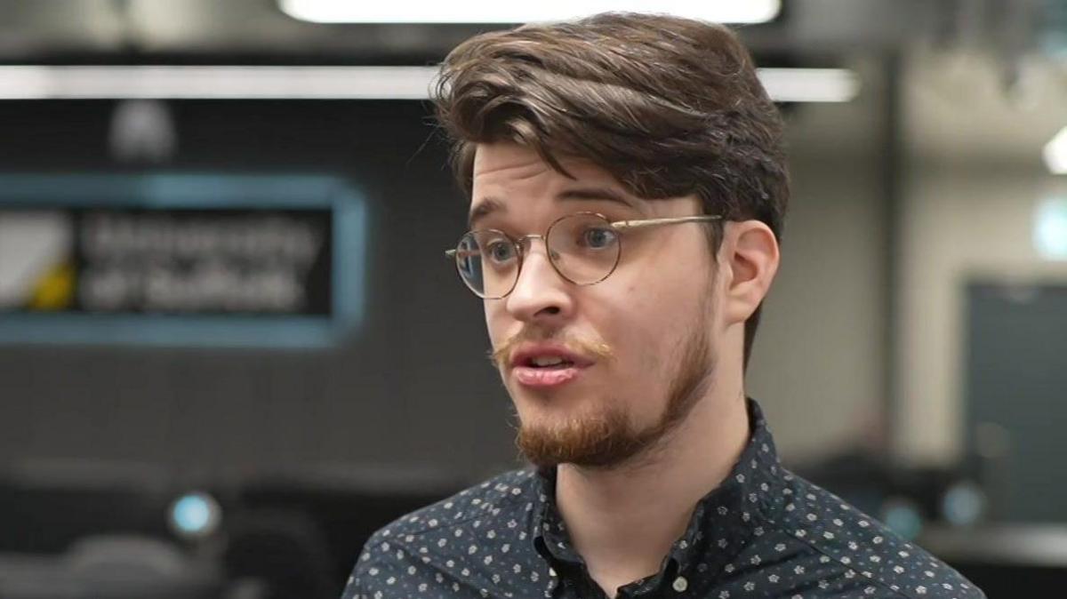 Charlie Smith was looking to the left of the camera. He had short brown hair and was wearing glasses and a blue shirt.