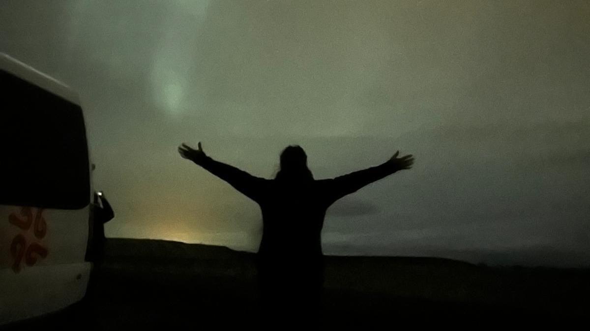 A silhouette of a woman against the backdrop of the Northern Lights in Iceland