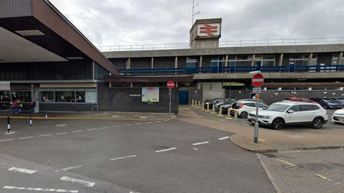 Exterior of Stafford station, with overhead canopy on the left, and a group of cars in the car park on the right