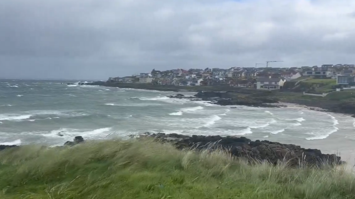 Waves along the Portstewart coast. Buildings and houses are in the distance.