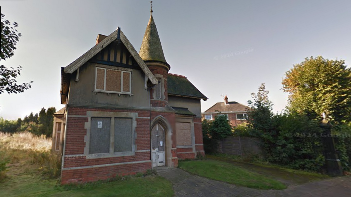 A Victorian red brick detached home, complete with a slate turret and arched doorway. All the house's windows are boarded up and it looks in need of renovation.