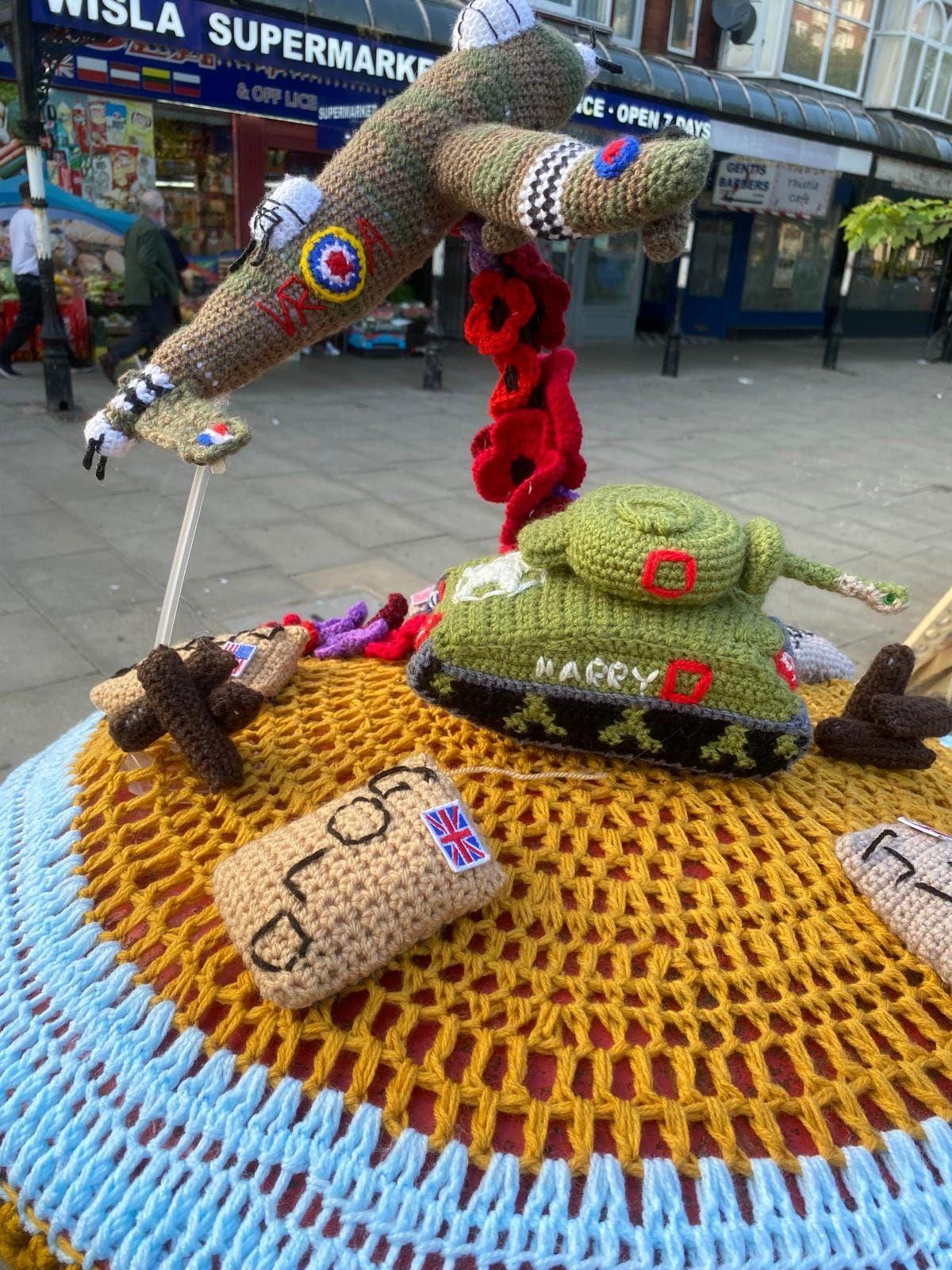 A crochet model of a Lancaster bomber and a tank on a post-box