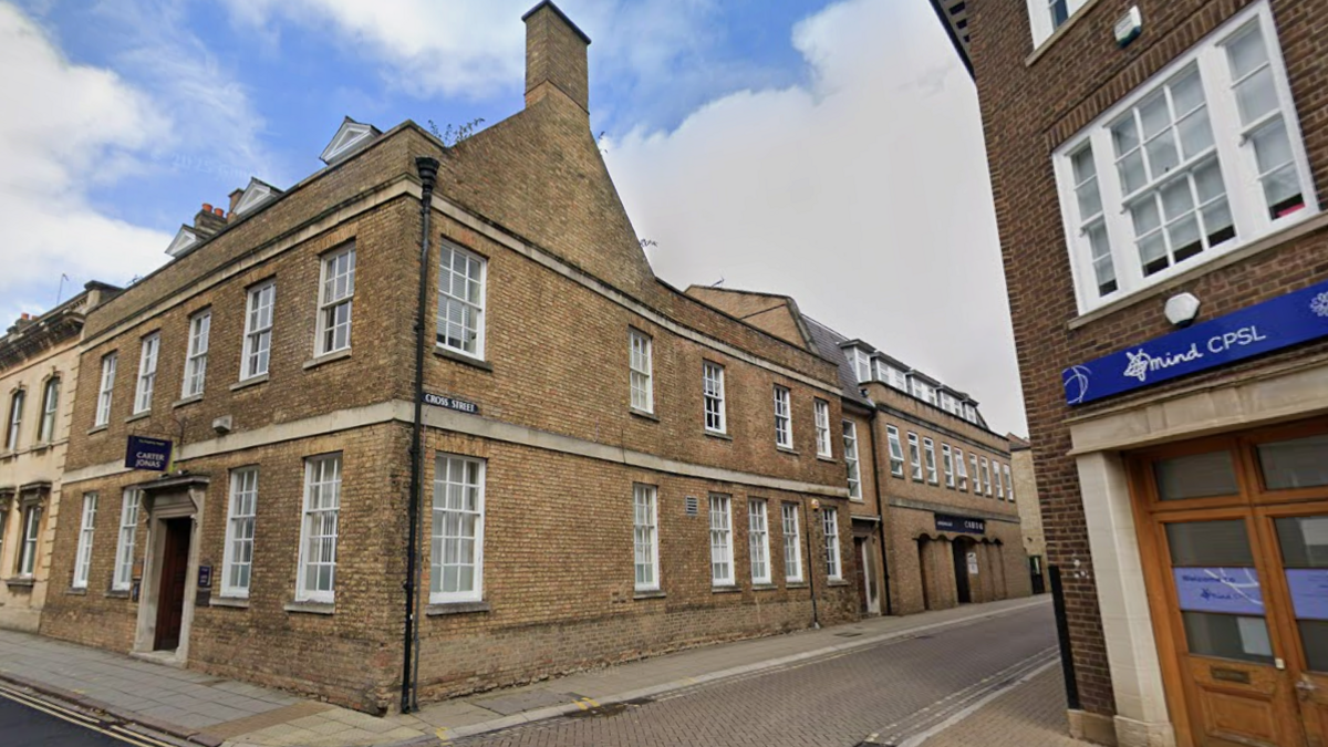 A double-storey brick building, with sash windows on both floors. The building sits on the corner of two roads and there is a Mind charity shop across the road from it.