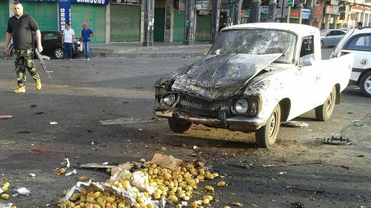 Picture from Syrian news agency (Sana) on July 25, 2018 shows a member of the security forces walking past a truck damaged in a suicide attack in Sweida