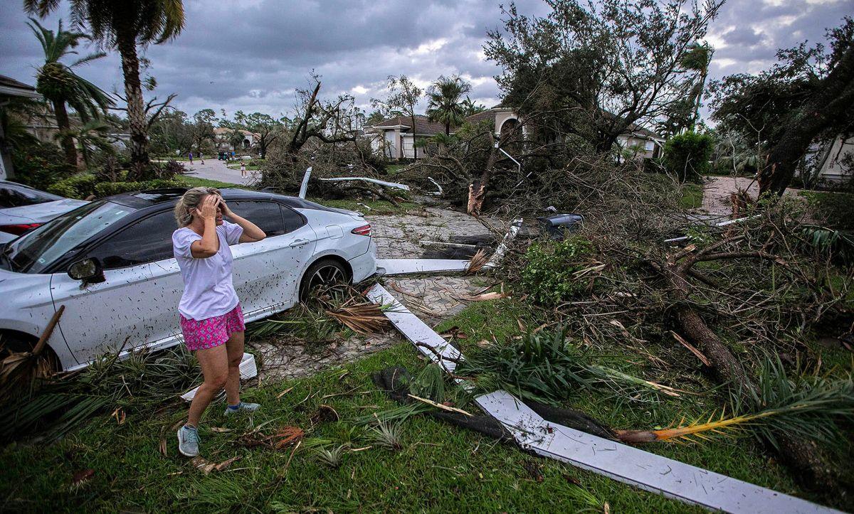 Marie Cook holds her head and reacts to the damage to her home in the Binks Estates community, with a car and felled trees in shot, in Wellington, Florida, U.S. October 9, 2024