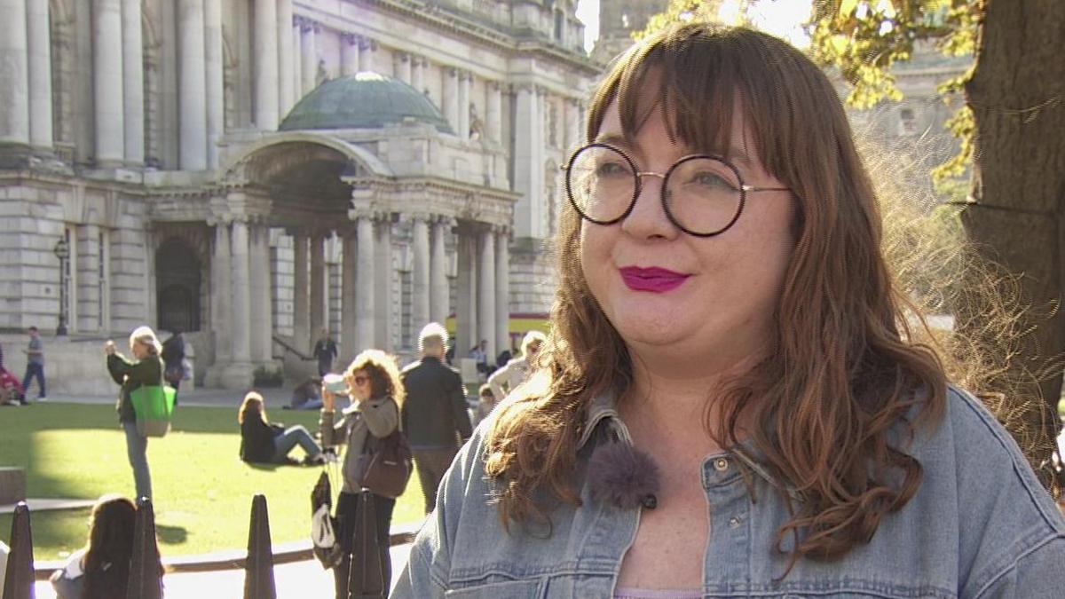 Green Party councillor Áine Groogan standing in front of Belfast City Hall 