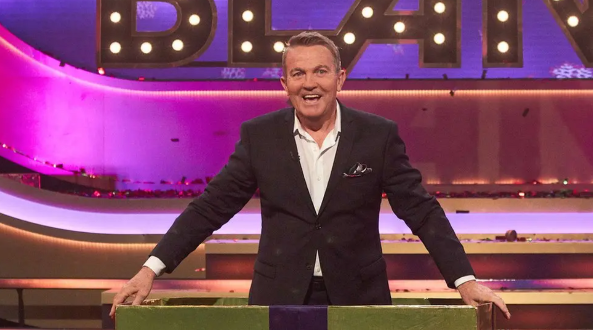 Bradley Walsh hosted the recent Blanketty Blank Christmas special, photo of Bradley in a suit standing behind a podium smiling.