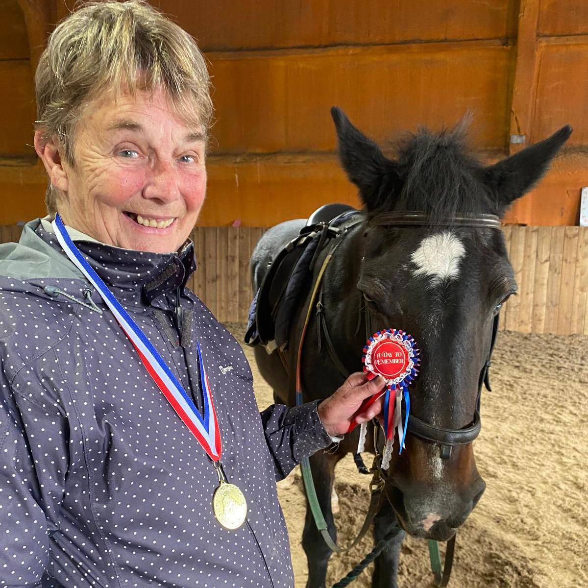 Barbara Heslip with a medal and rosette after her day of horse riding