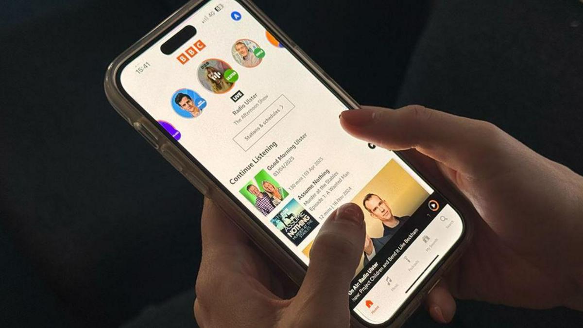 Hands with pink nail polish hold an iPhone with the BBC Sounds app on the screen.