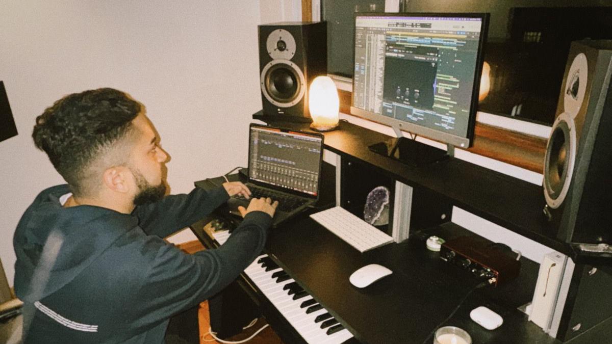 Kishan Thakrar in a studio, by screens, and a keyboard, producing music. 