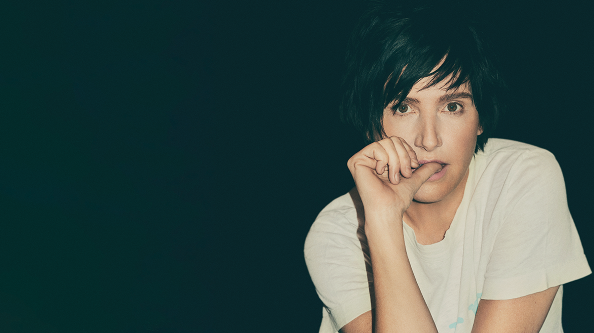 Texas lead singer Sharlene Spiteri sat in a white T shirt with her thumb in her mouth and leaning on her elbow - against a black backdrop 