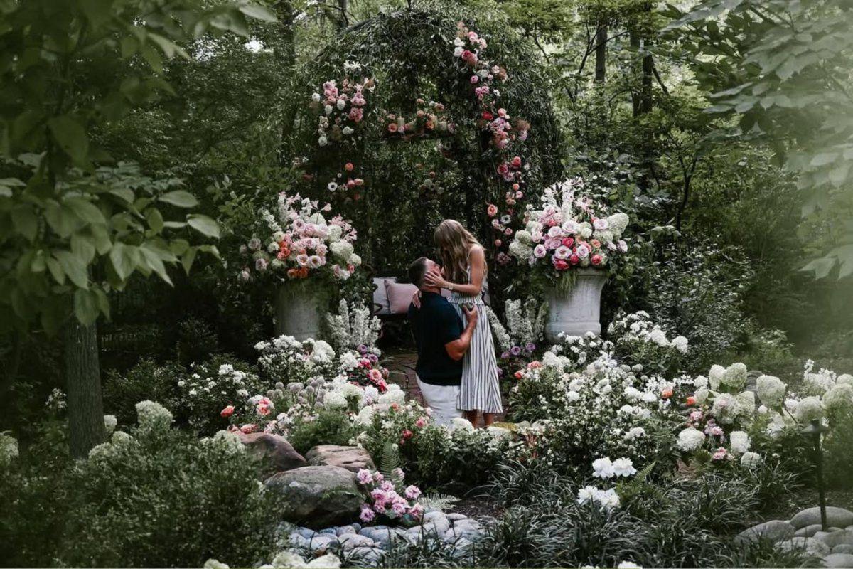 The couple surrounded by flowers like roses, anemones, delphiniums and hydrangeas for the proposal.