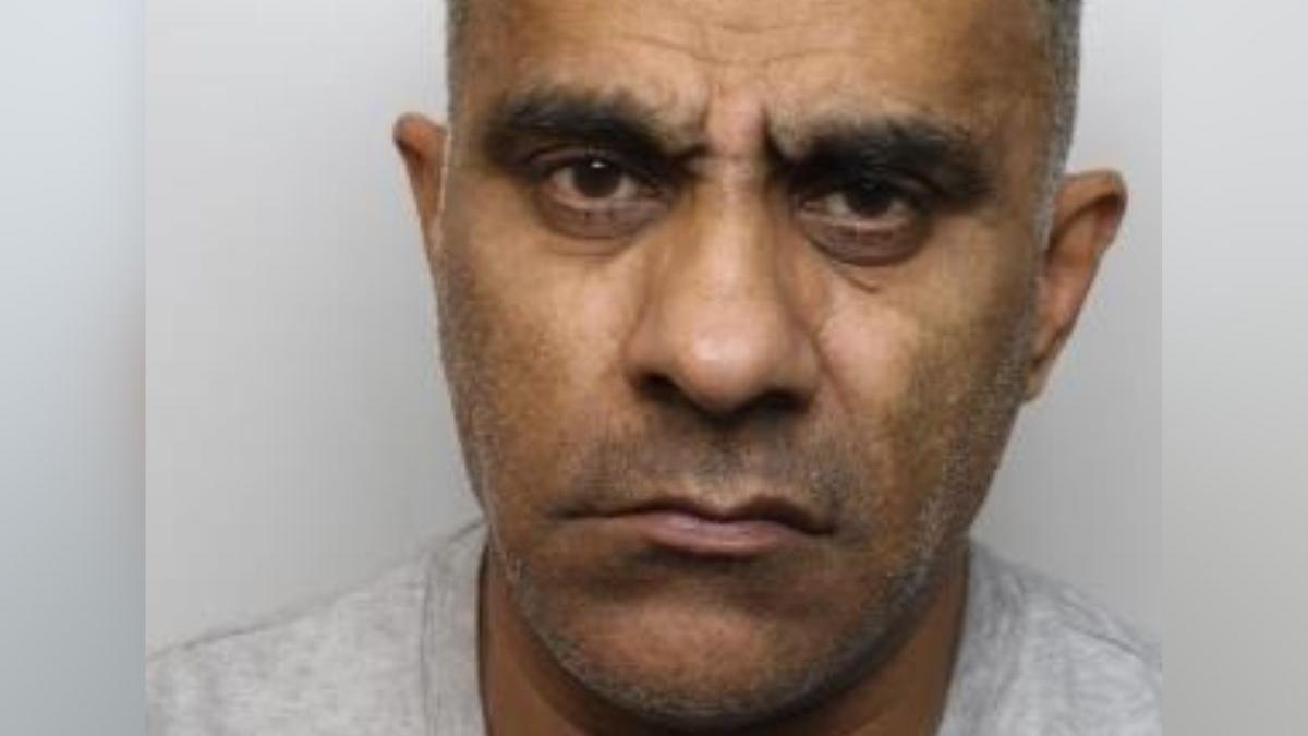 A man with short grey hair and brown eyes. He is wearing a grey t-shirt and is in front of a grey background. It is a custody photo.